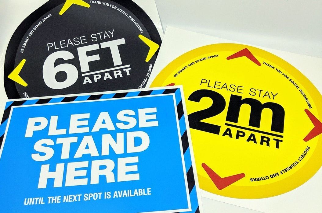 Assortment of social distancing floor decals including black 6FT, yellow 2m, and blue Please Stand Here vinyl stickers