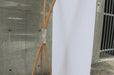 Side angle view of a bamboo X-stand display showing the blank white reverse side of the vinyl banner attached to natural bamboo support arms