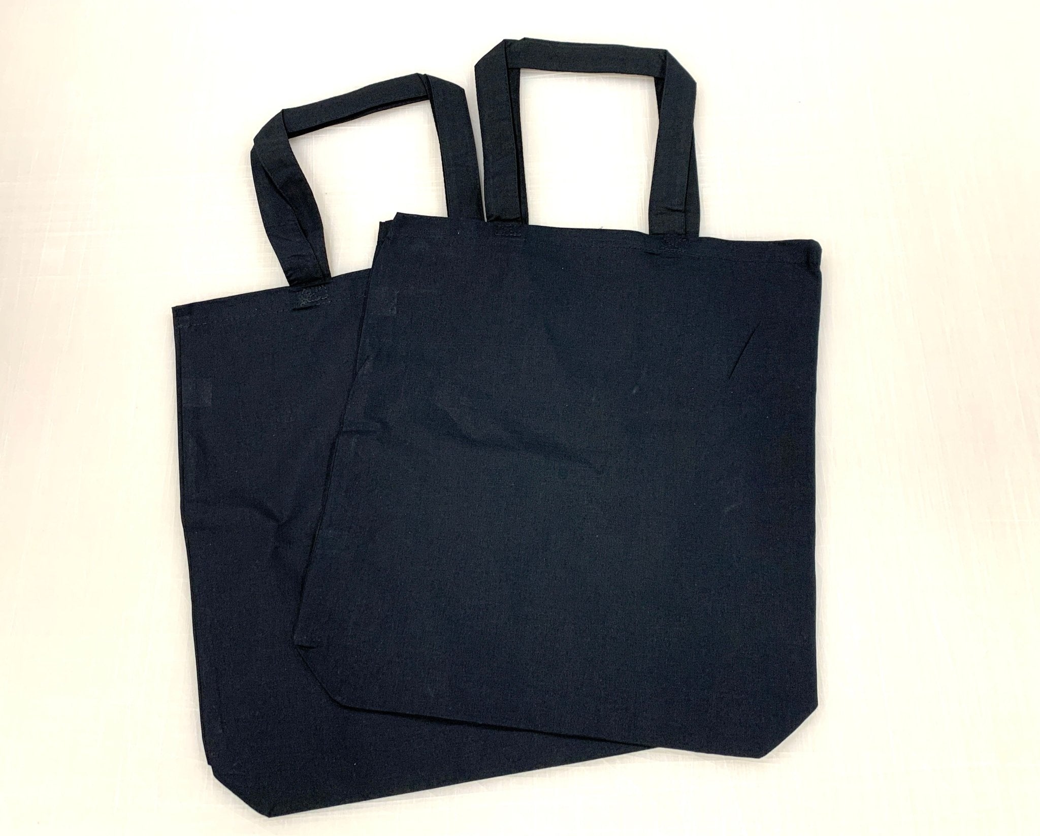 Two black 6oz unprinted cotton blank tote bags with handles displayed flat - Clubcard Vancouver