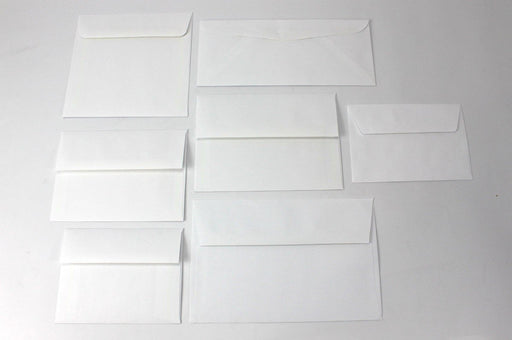 Grid arrangement of blank white wove envelopes in various standard card and letter sizes displayed on a light surface.