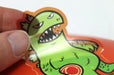 Hand peeling a clear custom shape vinyl sticker sample featuring a Clubcard's green cartoon dinosaur mascot illustration, printed by Clubcard Vancouver