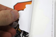 Hand peeling the paper backing off a custom shape vinyl sticker sample showing the adhesive layer, printed by Clubcard Vancouver