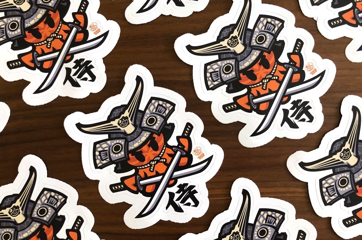 Custom shape vinyl sticker samples featuring a stylized samurai warrior character illustration with swords, printed by Clubcard Vancouver