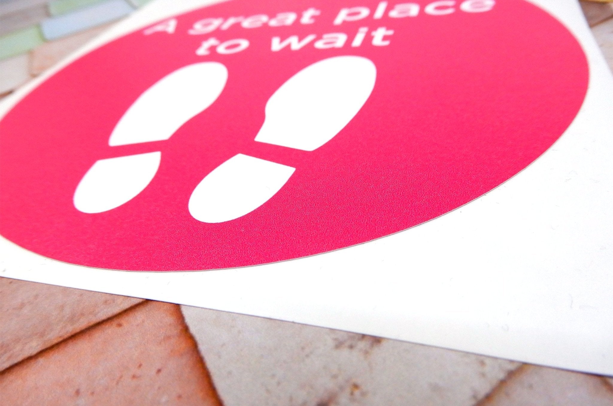 A fanned-out stack of bright pink circular vinyl floor stickers printed with white footprints and 