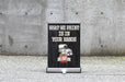 Extra large 18x24.5 inch table-top retractable banner stand displaying custom artwork "What We Print Is In Your Hands" with a silver base against a concrete wall.