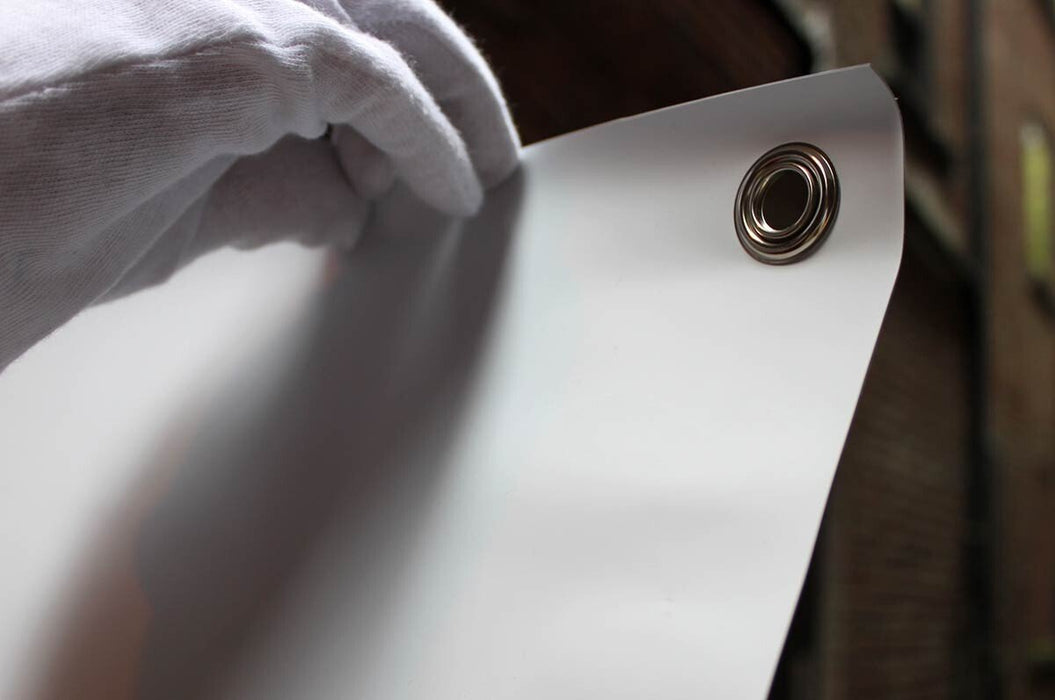 Close up view of a gloved hand holding the top corner of a vinyl replacement banner to showcase a metal grommet