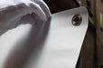 Close up view of a gloved hand holding the top corner of a vinyl replacement banner to showcase a metal grommet