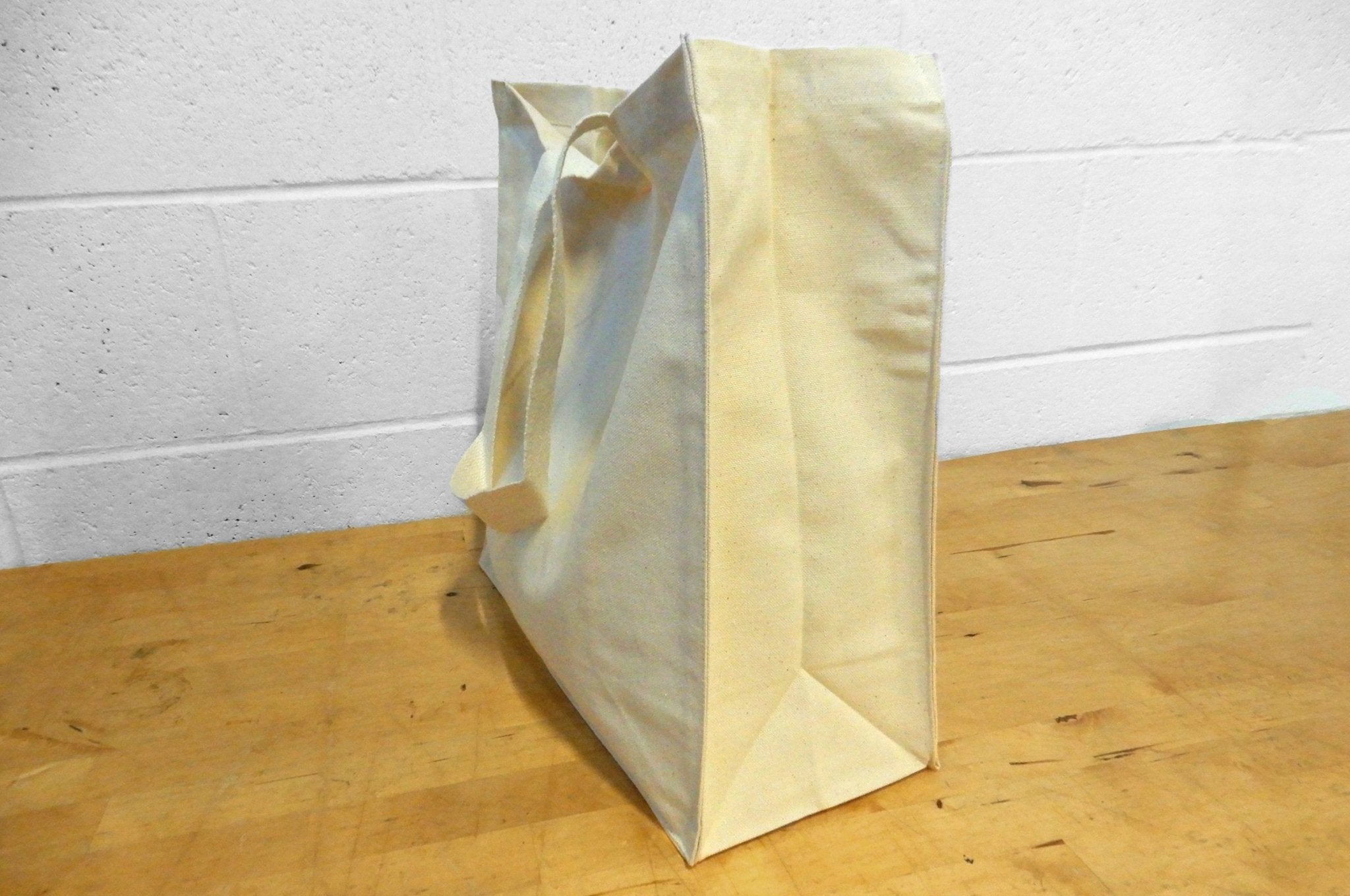 Heavyweight 12oz natural cotton canvas tote bag with side and bottom gusset standing on a wood surface - Clubcard Vancouver