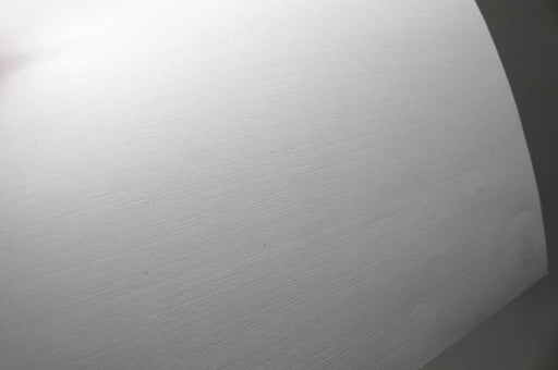 Close-up view of a curved sheet of white 70lb linen uncoated letterhead showing its textured surface.