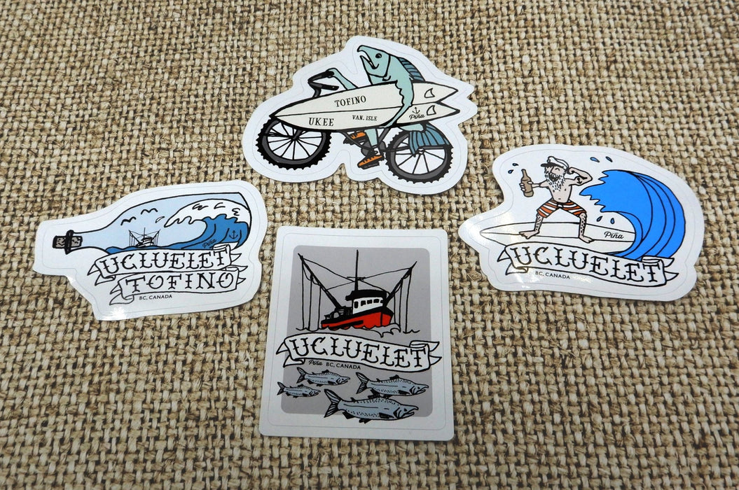 Custom shape vinyl sticker samples featuring Ucluelet and Tofino coastal lifestyle illustrations on a burlap background, printed by Clubcard Vancouver