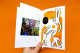 Hands holding open an illustrated saddle stitched zine printed in Vancouver