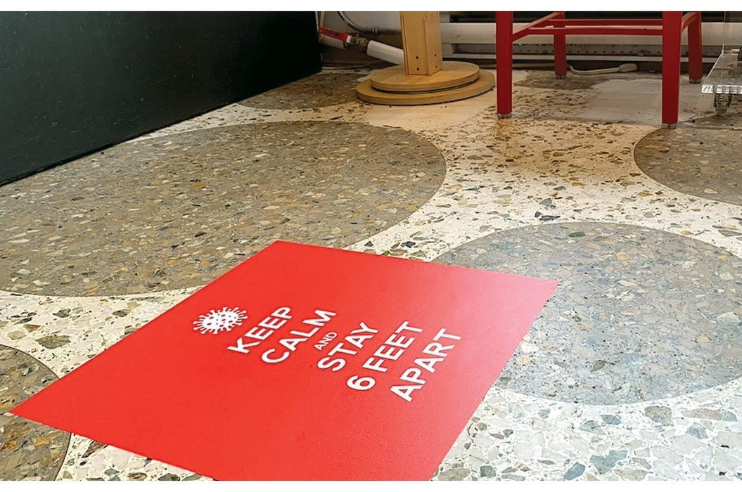 Red square floor decal reading Keep Calm and Stay 6 Feet Apart on a terrazzo tiled floor.