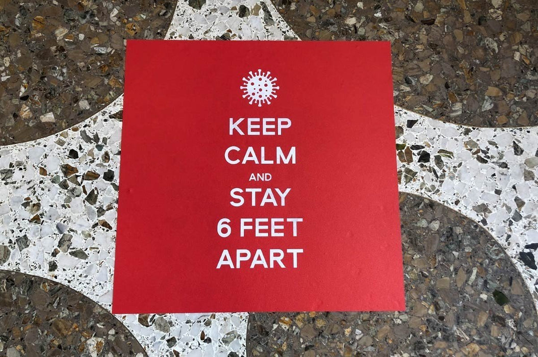 Red square floor decal reading Keep Calm and Stay 6 Feet Apart on a terrazzo tiled floor