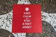 Red square floor decal reading Keep Calm and Stay 6 Feet Apart on a terrazzo tiled floor