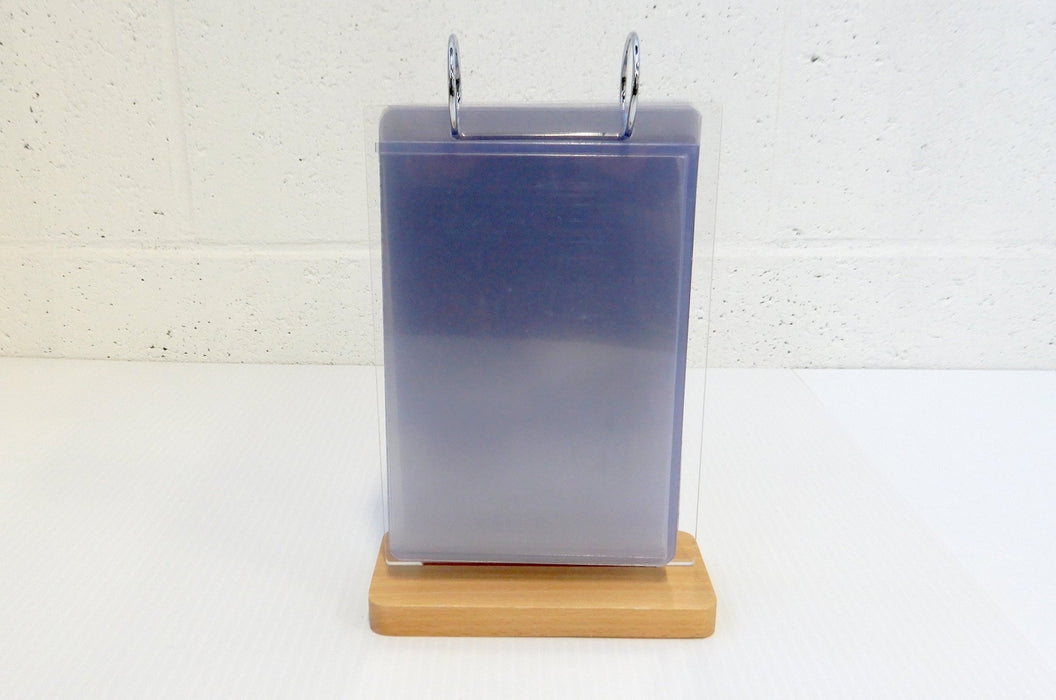 Tabletop acrylic flip menu stand with 5.75 x 8 inch clear pockets and metal binder rings on a wooden base