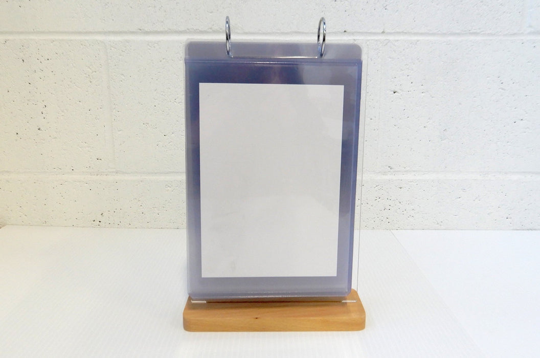 Front view of a tabletop acrylic flip menu stand with a white paper insert inside a 5.75 x 8 inch clear display pocket on a wooden base