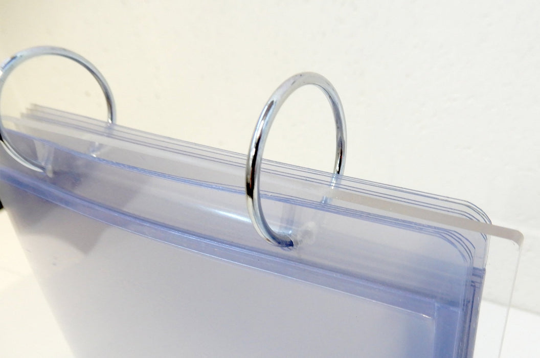 Close-up view of metal binder rings on a tabletop acrylic flip menu stand with 5.75 x 8 inch clear display pockets