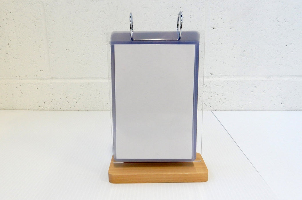 Front view of an acrylic flip menu stand with a white paper menu inserted inside a clear display pocket on a wooden base
