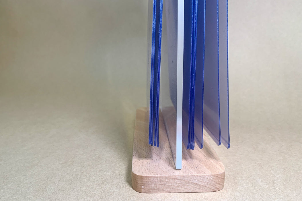 Side view of clear display pockets with blue protective film on an acrylic flip menu stand with a wooden base