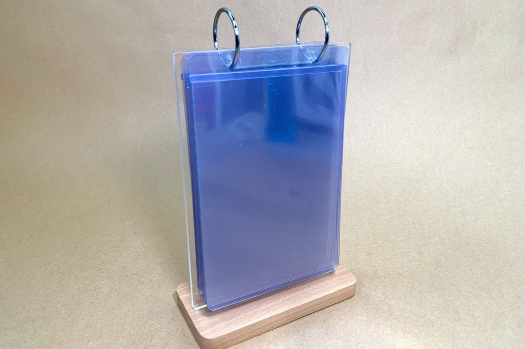 Three-quarter view of a tabletop acrylic flip menu stand with multiple stacked clear display pockets on a wooden base
