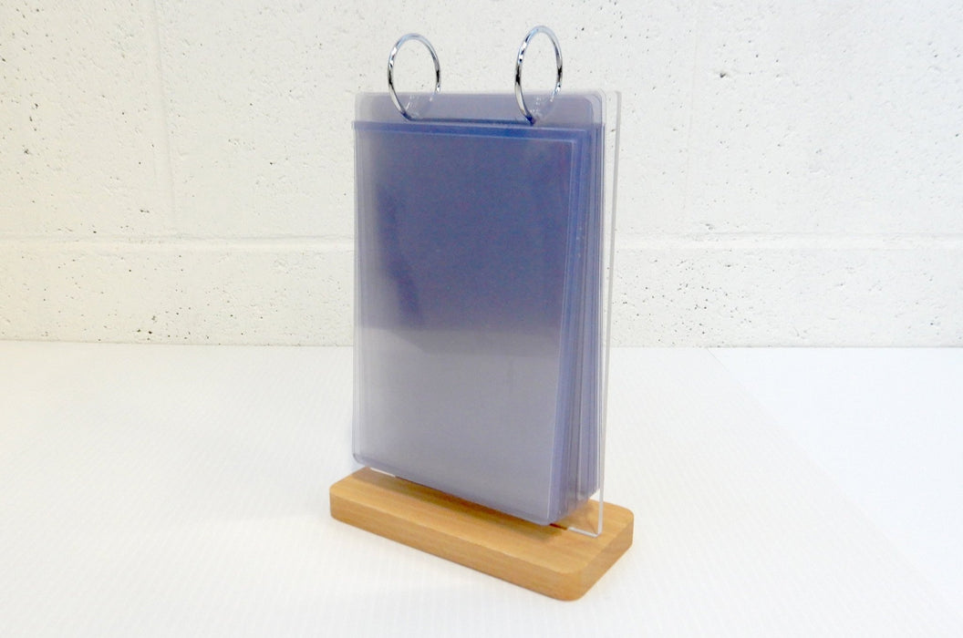 Three-quarter view of a tabletop acrylic flip menu stand showing multiple clear display pockets stacked together on a wooden base