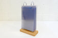 Three-quarter view of a tabletop acrylic flip menu stand showing multiple clear display pockets stacked together on a wooden base