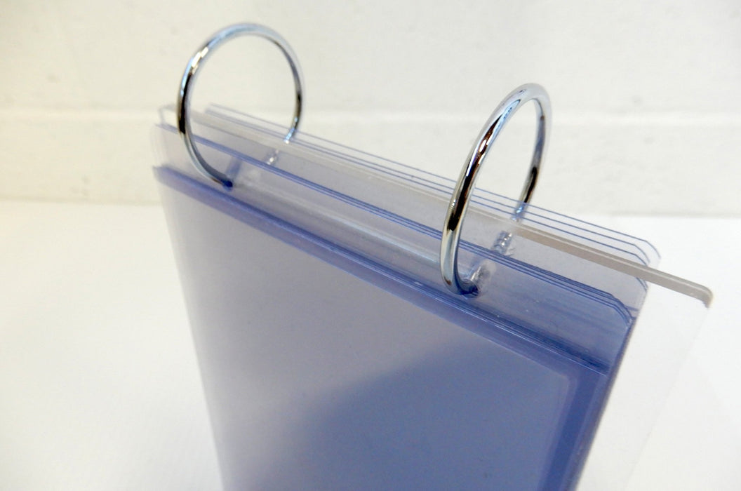 Top-angle view of open metal binder rings attached to the top of an acrylic flip menu display stand holding clear pockets