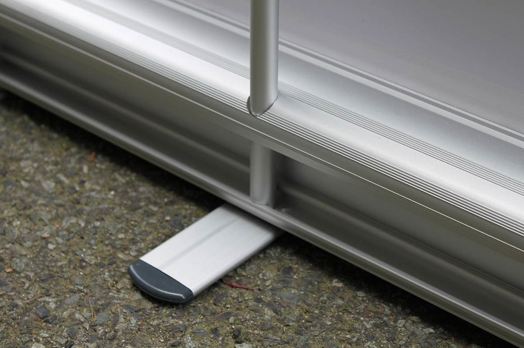 Close-up view of the silver aluminum cassette base and extended stabilizing foot on an extra-large tabletop retractable banner stand.