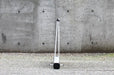 Rear view of an extra large table-top retractable banner stand displaying the silver aluminum base and vertical support pole set against a concrete wall.