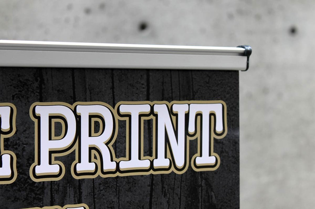 Close-up view of the top aluminum clamp rail and end clip securing the printed vinyl graphic on an extra-large tabletop retractable banner stand.