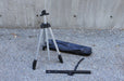 Compacted folding aluminum easel stand with transportation bag on a grey concrete background.