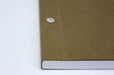 Close up of the binding of a closed chicago screw notebook with kraft brown cover, white pages and silver screws.