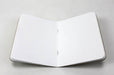 Open natural kraft pocket notebook with saddle stitch binding and white dotted pages.