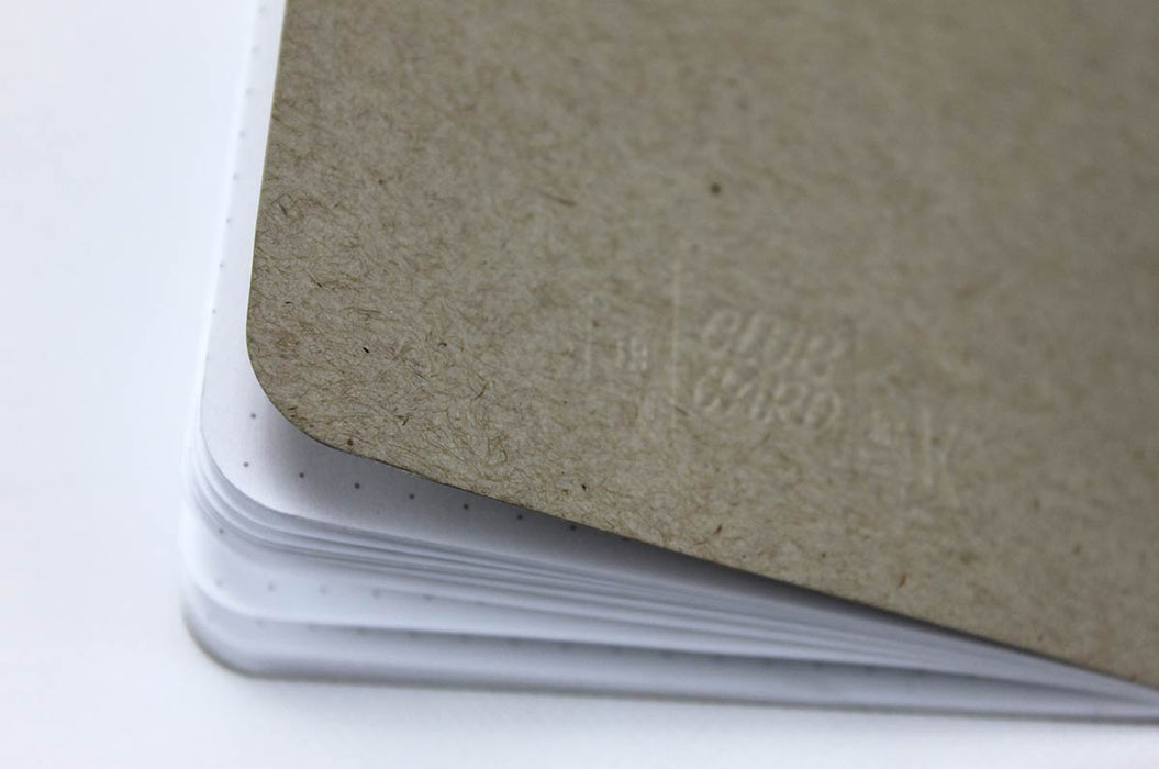 Close up of the back of a natural kraft pocket notebook with white dotted pages and the Clubcard logo embossed on the cover.